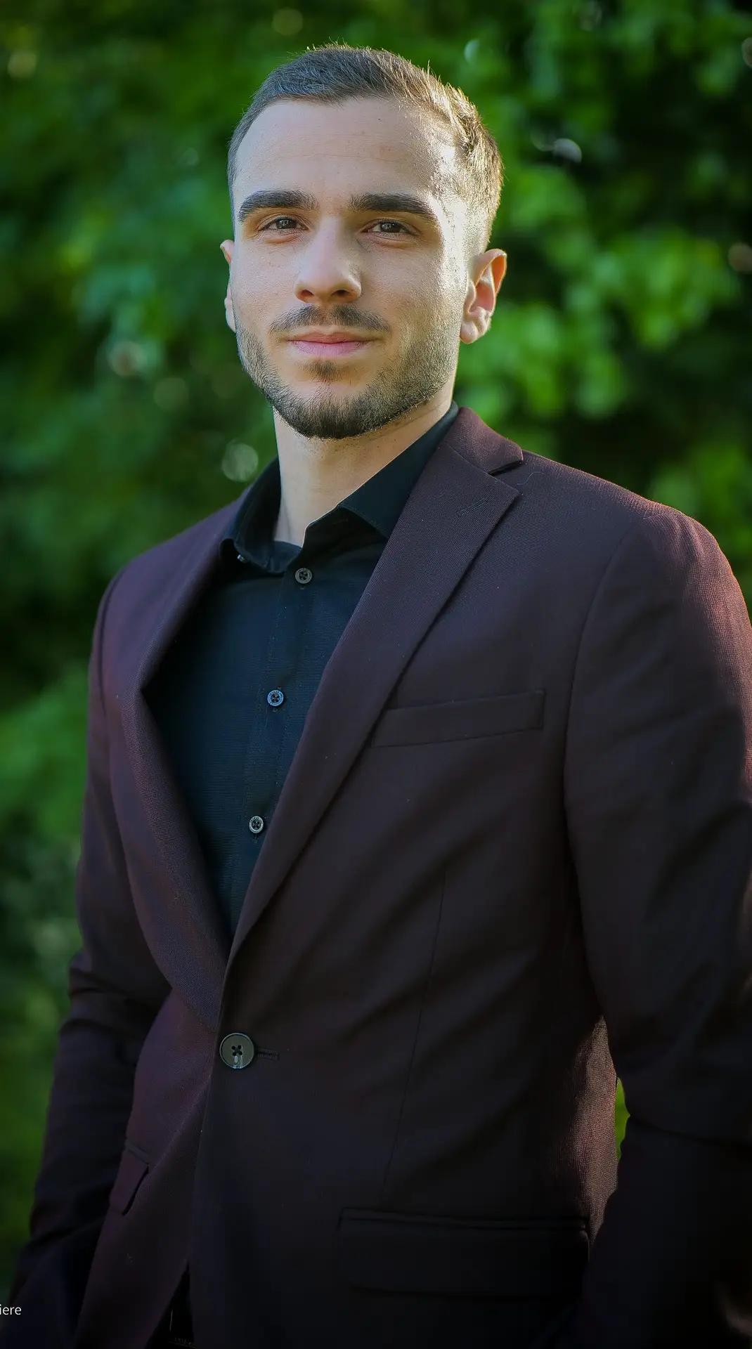 Kyliam LIERE, conseiller en gestion de patrimoine regarde l'objectif habillé en costume rouge.